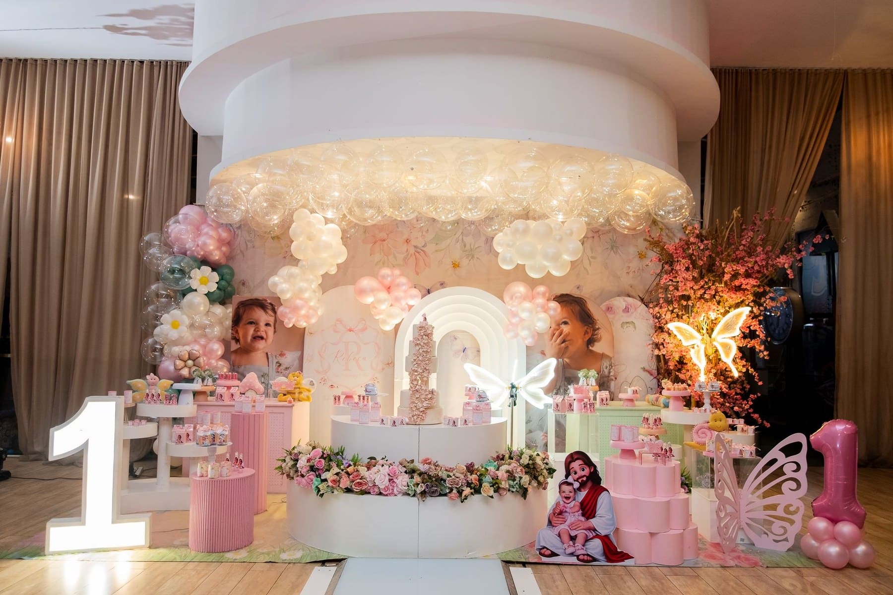 Decoração de aniversário infantil de 1 ano com bolo, flores e detalhes em tons pastel.