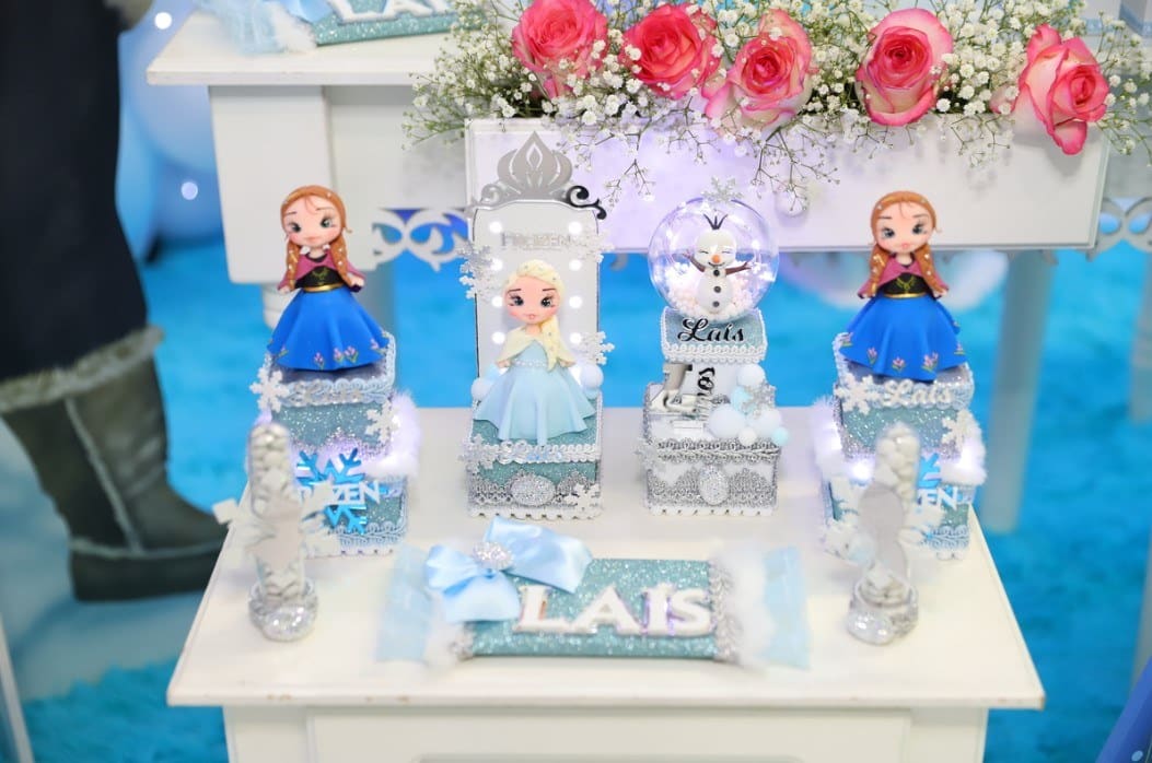 Decoração de festa infantil com tema Frozen, bolo e mesa de doces.